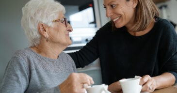 Homecarer serving tea to elderly woman